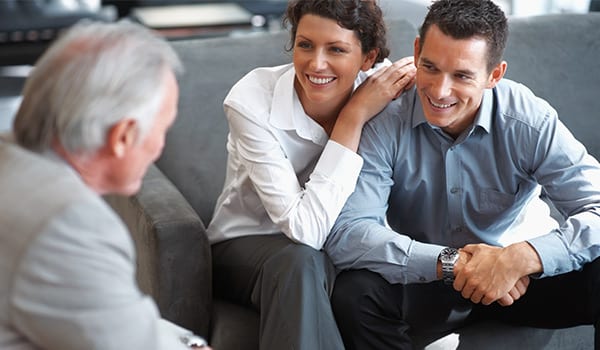 Couple smiling and looking at an insurance agent